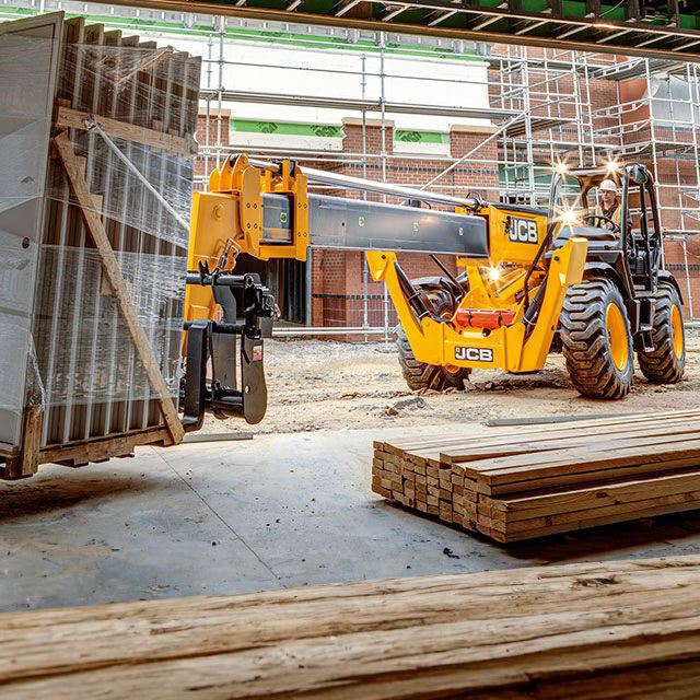 14,000 lb telescopic forklift lifting heavy materials at a construction site, showcasing its extendable boom and robust build ideal for high-load applications.