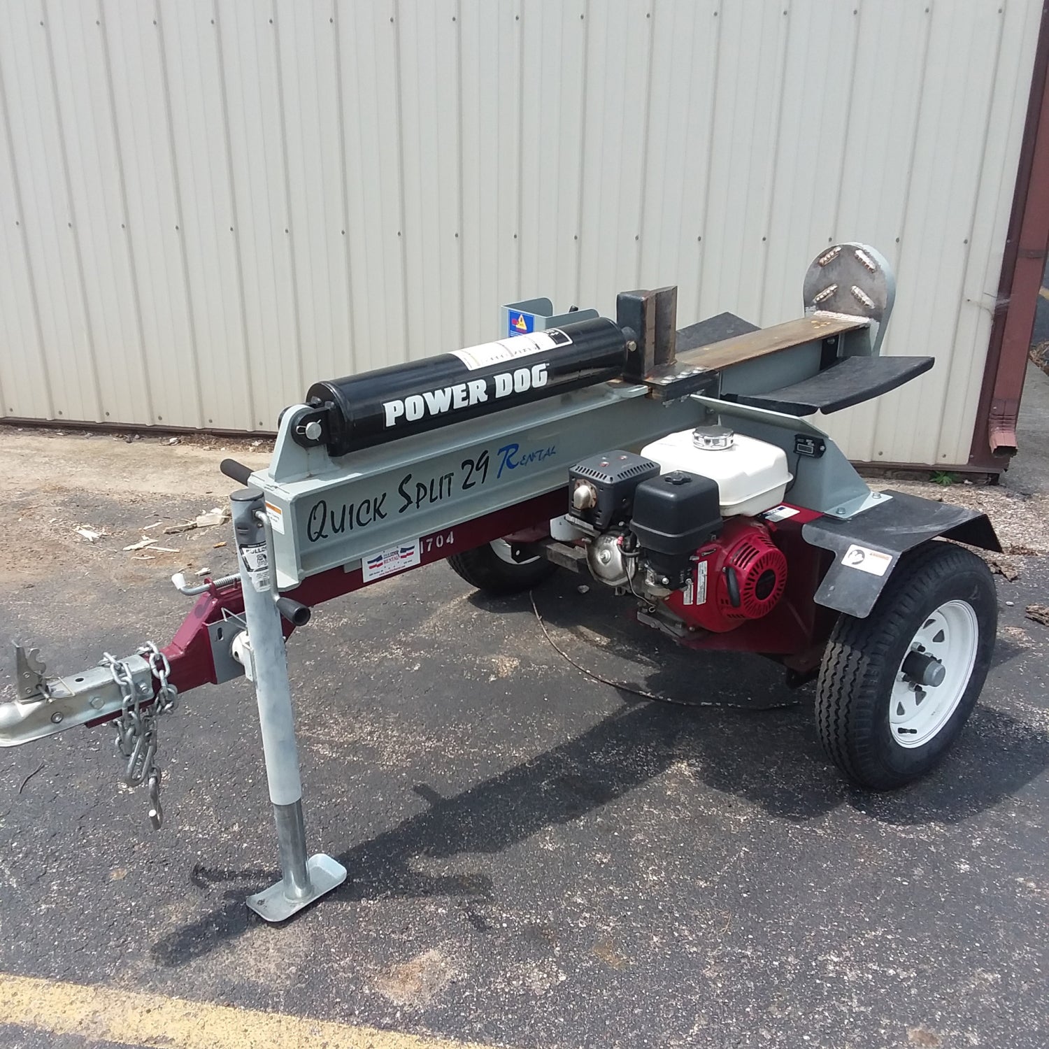 Tow-behind log splitter trailer on asphalt, showcasing a powerful hydraulic mechanism designed for efficient wood splitting, ideal for residential and commercial use.